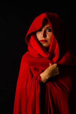 Koyu arkaplanda kırmızı pelerinli güzel bir kadın dramatik ve fantastik bir çekim 