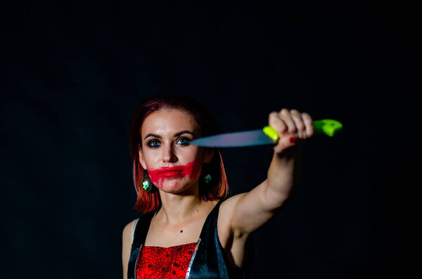 Gorgeous redhead woman with bloody knife in her hand close-up, Halloween concept 