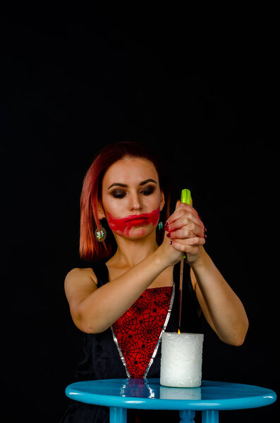 A witch is fortune teller in black robe holds a stone amethyst pendulum on chain above her hand. Magical ritual. Tarot cards, white candles. Occult, esoteric and divination concept. Mystic background.