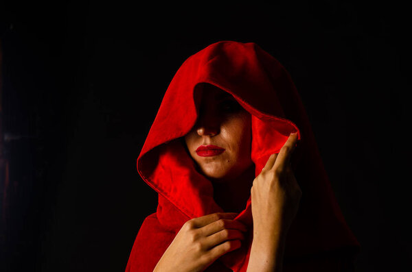 Beautiful woman in red cloak on dark background Dramatic and fantastic shooting