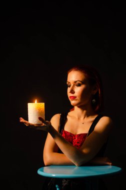 Gizemli sihirli yakın plan. Siyah arka planda izole bir şekilde yanan bir mumun üzerinde kadınların elleri beliriyor. Kehanet, kehanet ve kehanet kavramı..