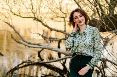 Güneşli bir günde nehir kenarında poz veren güzel çekici bir kadın. 