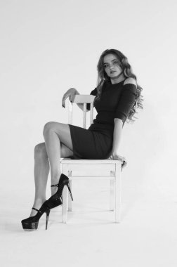 Uzun saçlı, topuklu ayakkabılı, beyaz stüdyo arka planında soyutlanmış güzel bir kadın. 