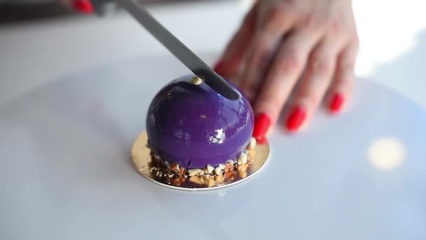 Mano femminile che taglia una torta viola su un tavolo bianco. torta di mousse. Delizioso dessert — Video Stock