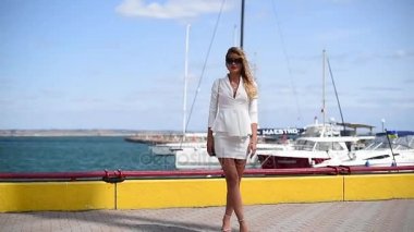 Sıcak günde yüz mavi deniz ve gökyüzü karşı saç koyarak kamera poz ciddi yüz ifadesi ile yavaş şirin kız. Giyimli kadın sarışın saçlı Avrupa görünüm