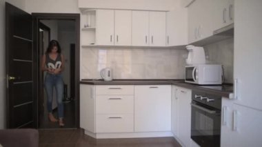 bir kız mutfağa girer ve bir su ısıtıcısı içerir. ince güzel rakam. Günaydın, güzel ayakların