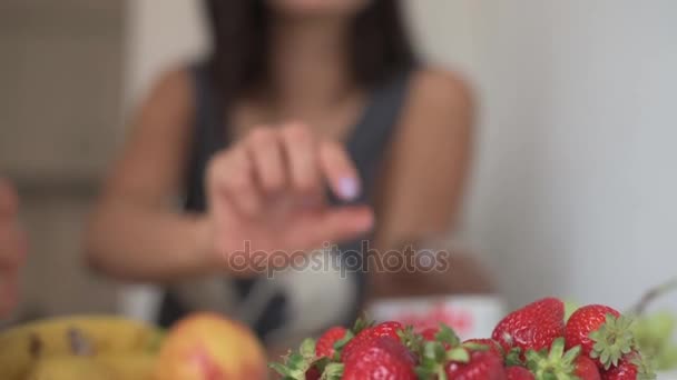 Flicka äter jordgubbar. på morgonen i köket av par i kärlek — Stockvideo