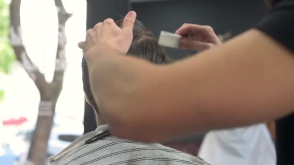 Парикмахер расчесывает волосы клиентов перед стрижкой. вид спереди — стоковое видео