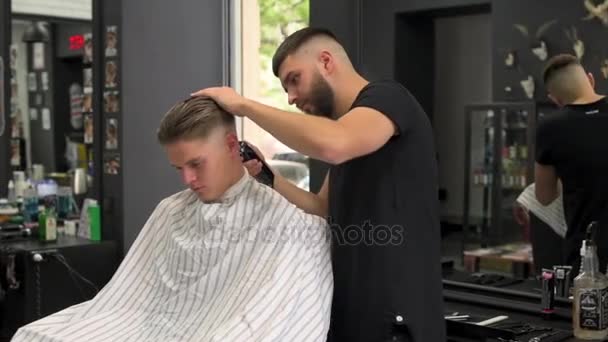 Peluquero corta el pelo de los clientes. vista lateral — Vídeo de stock