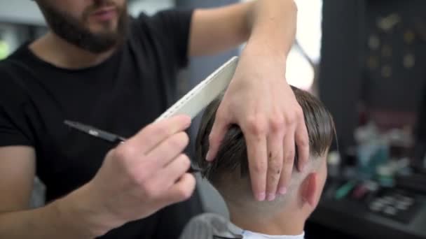 Berber cisaille un client avec des ciseaux à l'aide d'un peigne — Video