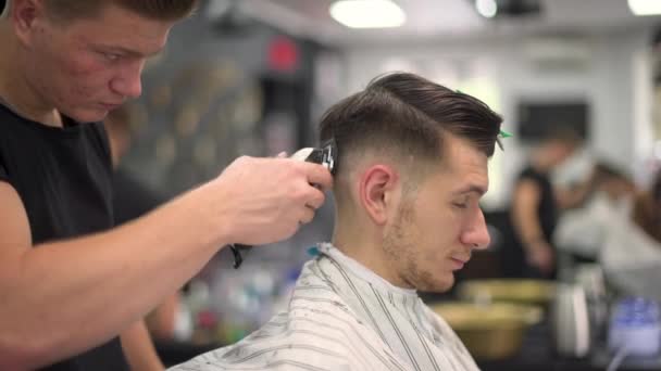 Barbeiro tosquia o cabelo dos clientes. vista lateral — Vídeo de Stock