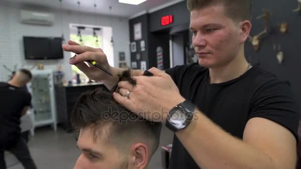 Berber shears a client with scissors using a comb — Stock Video
