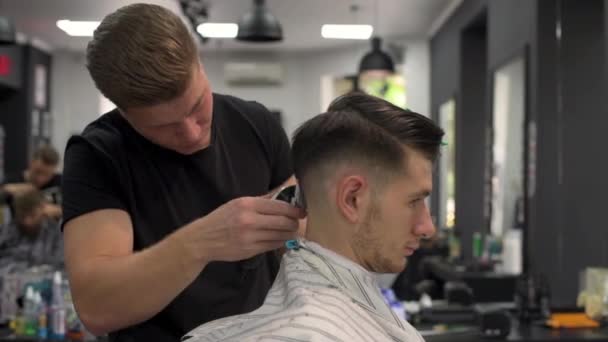 Barber shears the clients hair. side view — Stock Video