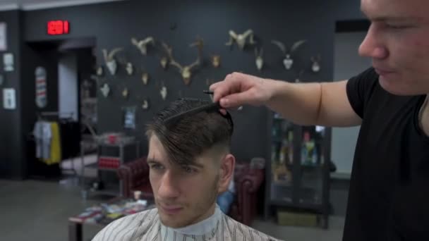 Barbeiro penteia o cabelo dos clientes antes de cortar. vista frontal — Vídeo de Stock