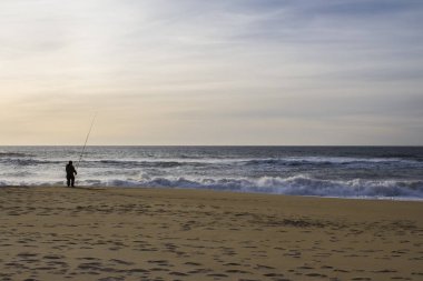 fırtınalı okyanus kıyısında yalnız balıkçı