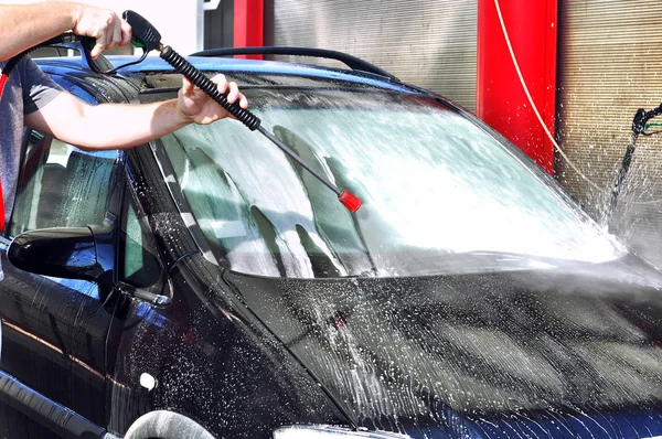 Cleaning Car Using High Pressure Water.Man washing his car under high pressure water in service