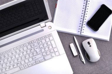 Office çalışma alanı ile cep telefonu ve dizüstü bilgisayar klavye kadar yakın ve fare ile defter görünümünü yukarıda yüksek, kalem ve usb flash gri masanın üzerinde. Çalışma Resepsiyon Masa kavramı 