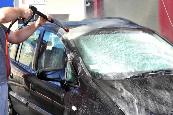 Cleaning Car Using High Pressure Water. Man washing his car under high pressure water in service