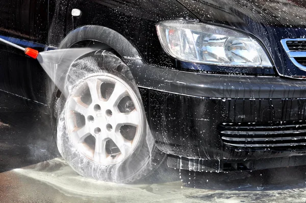 Cleaning Car Using High Pressure Water. Man washing his car under high pressure water in service