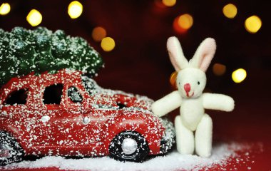 Kırmızı arka planda Noel arabası ve çam ağacı ışıkları.