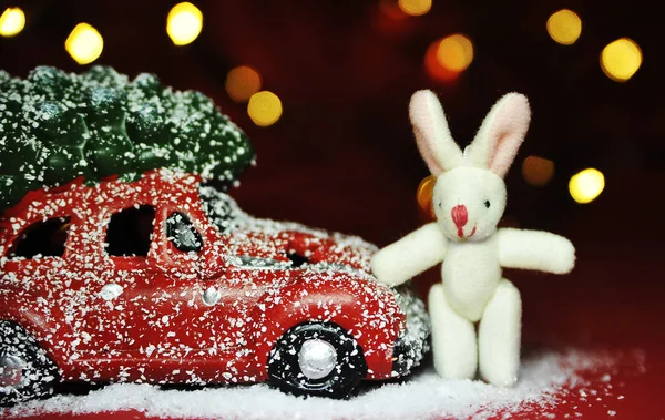 Kırmızı arka planda Noel arabası ve çam ağacı ışıkları.