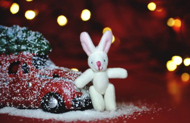 Kırmızı arka planda Noel arabası ve çam ağacı ışıkları.