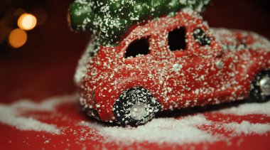 Kırmızı arka planda Noel arabası ve çam ağacı ışıkları.