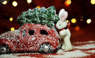Kırmızı arka planda Noel arabası ve çam ağacı ışıkları.