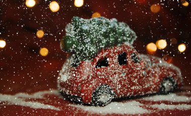 Kırmızı arka planda Noel arabası ve çam ağacı ışıkları.