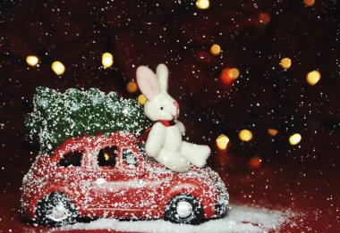 Kırmızı arka planda Noel arabası ve çam ağacı ışıkları.