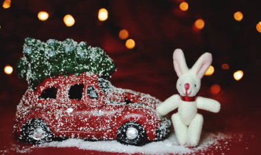 Kırmızı arka planda Noel arabası ve çam ağacı ışıkları.