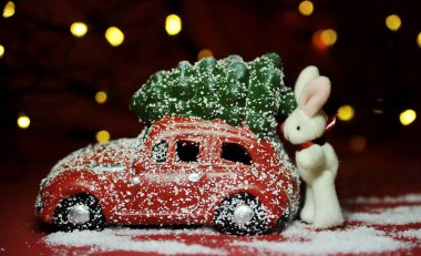 Kırmızı arka planda Noel arabası ve çam ağacı ışıkları.