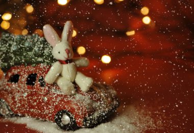 Kırmızı arka planda Noel arabası ve çam ağacı ışıkları.