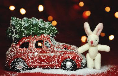 Kırmızı arka planda Noel arabası ve çam ağacı ışıkları.