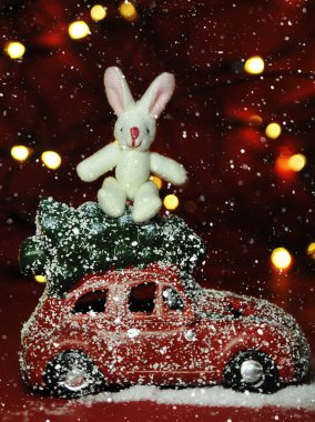 Kırmızı arka planda Noel arabası ve çam ağacı ışıkları.