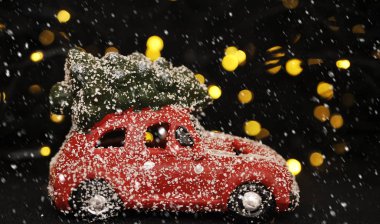 Kırmızı arka planda Noel arabası ve çam ağacı ışıkları.