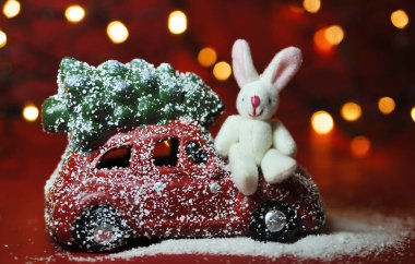 Kırmızı arka planda Noel arabası ve çam ağacı ışıkları.