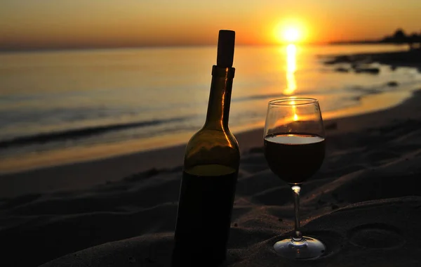 Wine glasses with red wine on sand on the beach. Valentine\'s Day concept.