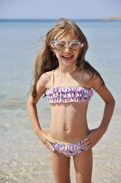 Şirin küçük kız sahilde eğleniyor. Yaz mevsimi kavramı.