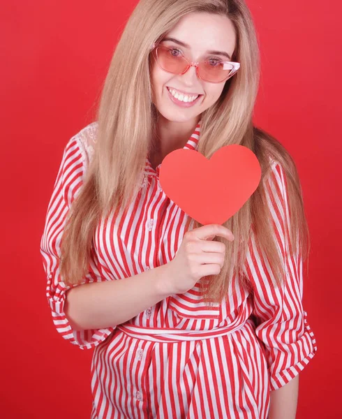 Χαμογελαστή Γυναίκα Γυαλιά Ηλίου Κόκκινη Καρδιά Στο Χέρι Ποζάροντας Κόκκινο — Φωτογραφία Αρχείου