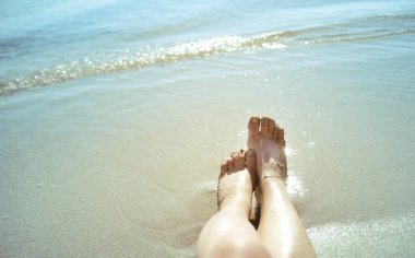Sahilde kadın ayakları. Yaz konsepti.