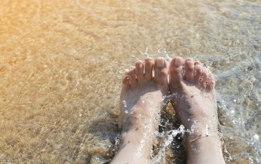 Sahilde kadın ayakları. Yaz konsepti.