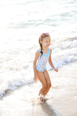 Summer time concept. Happy little girl plays on the beach. 