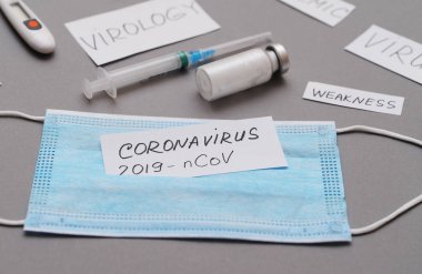Şırınga, aşı, koruyucu maske ve üzerinde Coronavirus yazan kağıt..