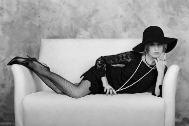 Kanepede poz veren güzel bir kadın. 20 'lik eski tarzda stilize fotoğraf.