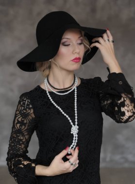 Kafasında tüy sargı bezi olan kadın gri arka planda poz veriyor. Retro biçimi.