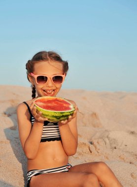 Yaz zamanı. Kumsalda karpuzlu küçük bir kız. Yaz konsepti.