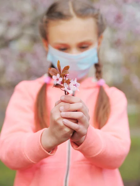 Schattig Meisje Beschermende Geneeskunde Masker Met Tak Van Bloeiende Kers — Stockfoto