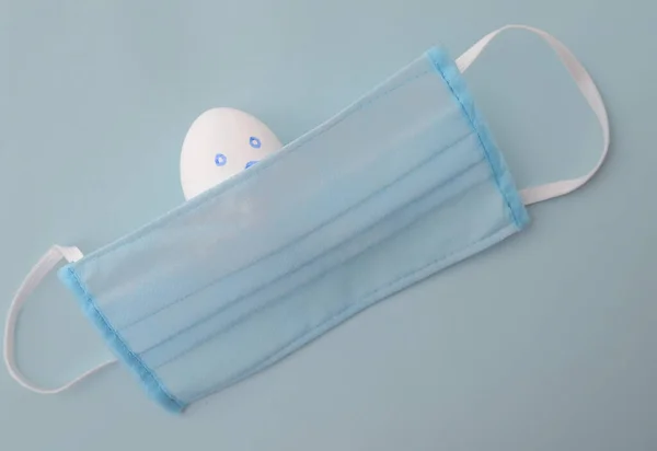 青い背景の保護マスクに卵がショックを受けました イースターの概念なし — ストック写真