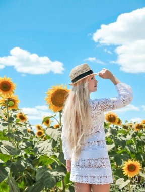 Caucasian beautiful woman in hat posing  with sunflowers.
